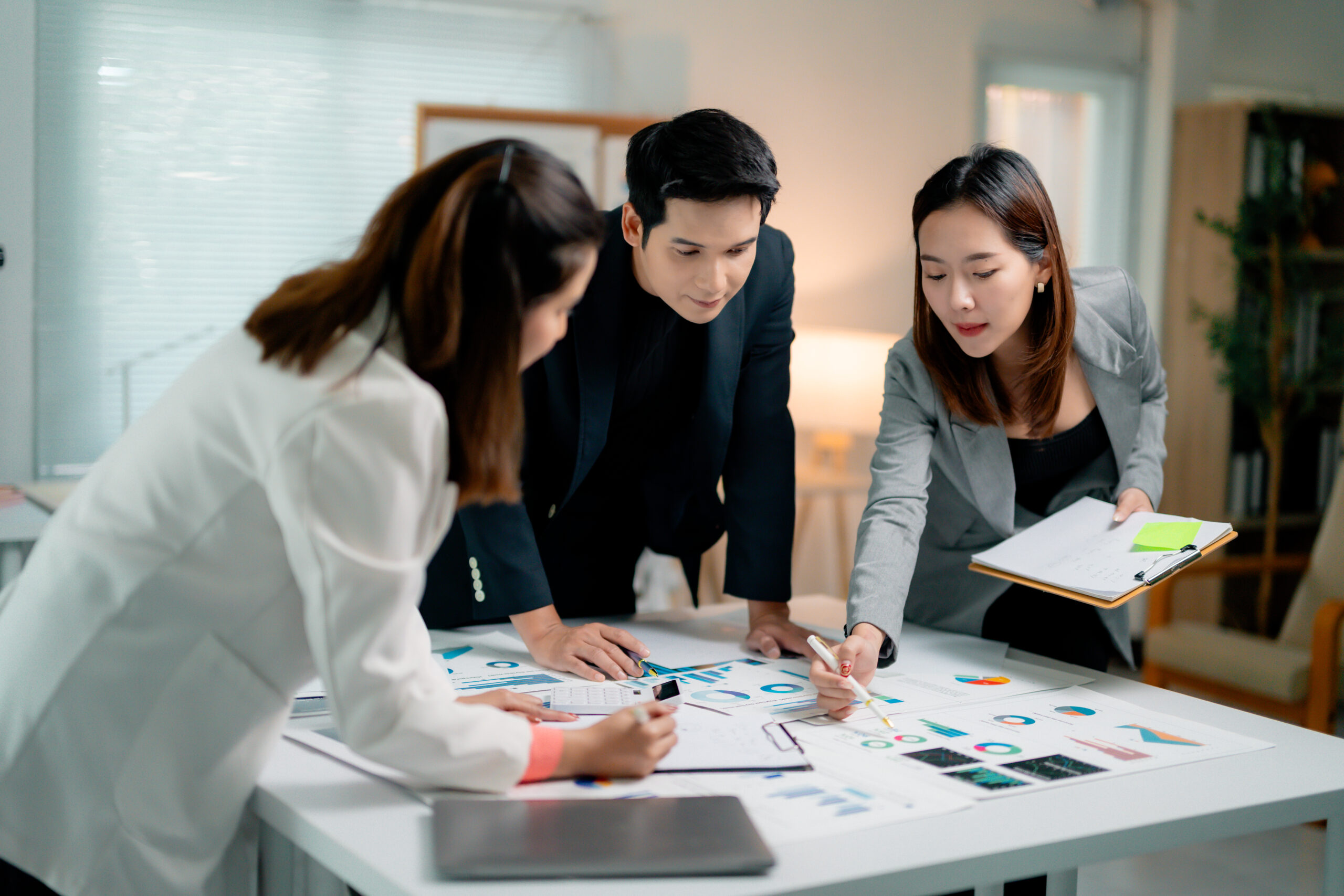 An Asian corporate team collaboratively analyzing financial charts and reports, demonstrating strategic insights for KPO solutions.
